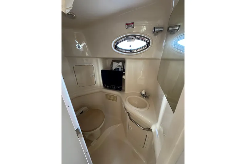 Slide: The Image of Compact bathroom in 2002 Sea Ray 310 Sundancer yacht, featuring toilet, sink, and porthole window. - 19