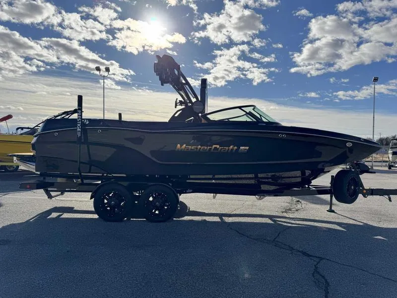Slide: The Image of 2025 MasterCraft XT24 boat on trailer under a bright, cloudy sky. - 6