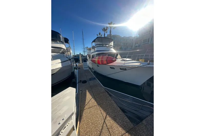 Slide: The Image of 1986 Lien Hwa 42 yacht docked under bright sunlight, with nearby boats and buildings. - 3