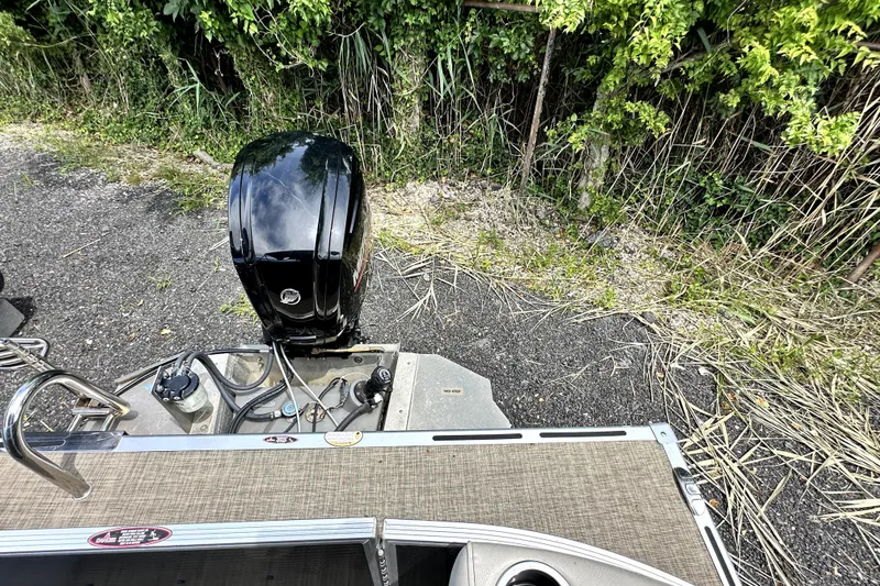 Slide: The Image of 2022 Cypress Cay Seabreeze 232 boat engine and deck, surrounded by greenery. - 12