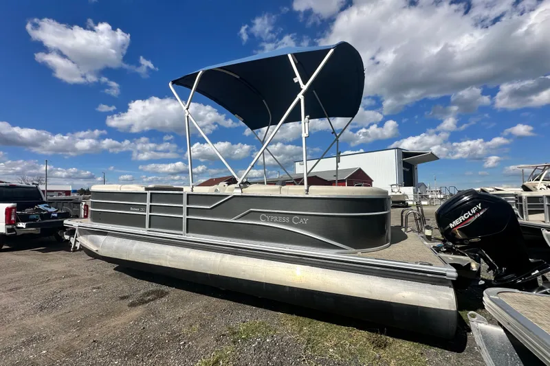 Slide: The Image of 2022 Cypress Cay Seabreeze 232 pontoon boat with canopy, parked outdoors under blue sky. - 2