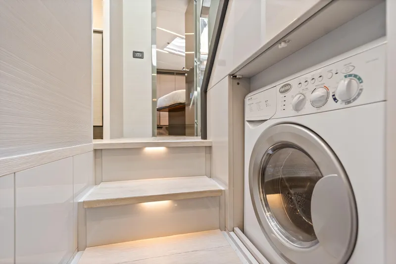 Slide: The Image of Laundry area in 2016 Pershing 62' yacht with modern washer and illuminated steps. - 38