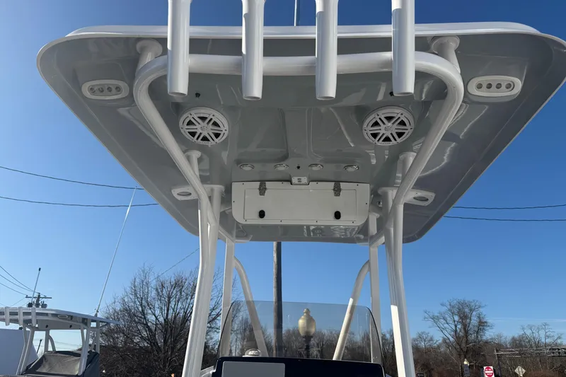 Slide: The Image of 2026 Sea Hunt Ultra 229 boat T-top with speakers and rod holders against blue sky. - 27