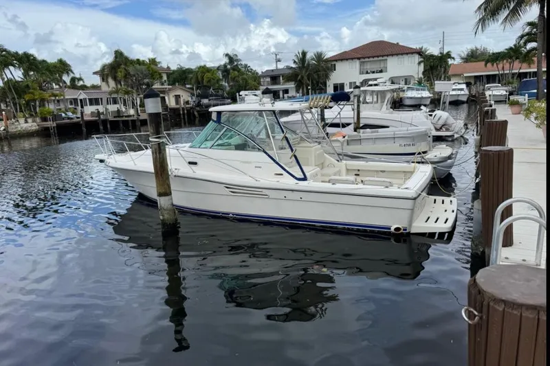 The Image of 2002 Pursuit 3000 Express boat docked in a marina with surrounding yachts. - 0