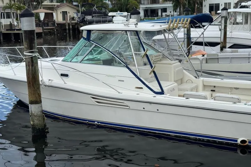 Slide: The Image of 2002 Pursuit 3000 Express boat docked in a marina, surrounded by other vessels. - 1