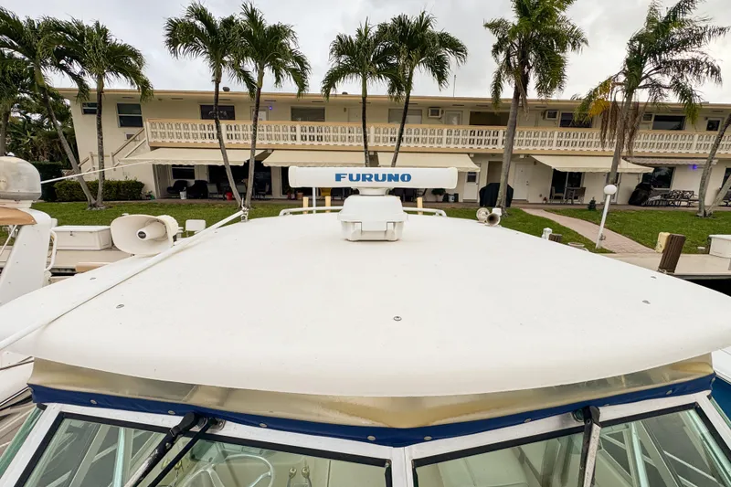 Slide: The Image of 2002 Pursuit 3000 Express boat with Furuno radar, docked near palm trees and a building. - 104