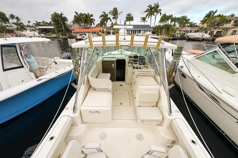Slide: The Image of 2002 Pursuit 3000 Express boat docked, featuring spacious seating and fishing rod holders. - 106