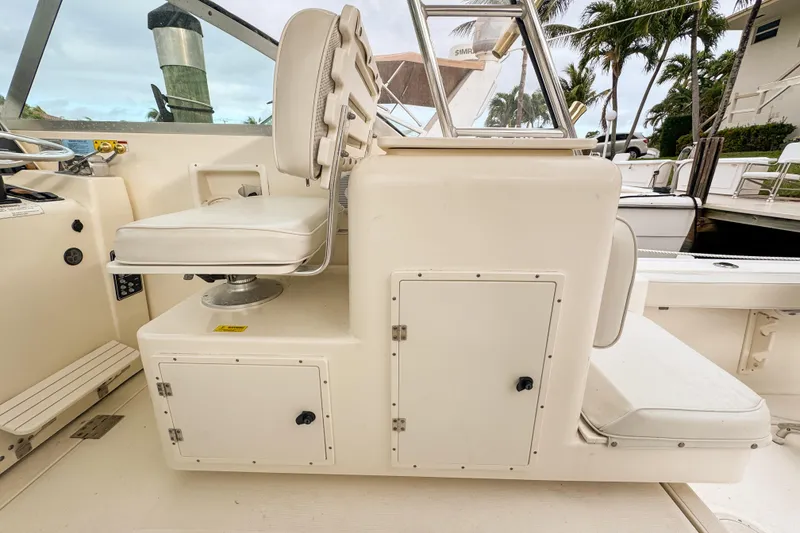 Slide: The Image of 2002 Pursuit 3000 Express boat interior with white seating and storage compartments. - 109