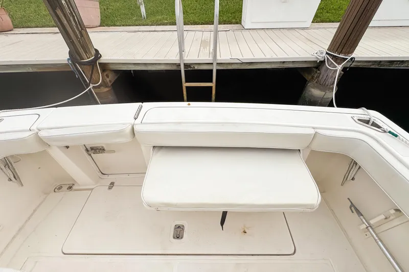 Slide: The Image of 2002 Pursuit 3000 Express boat interior with white seating and dock view. - 116