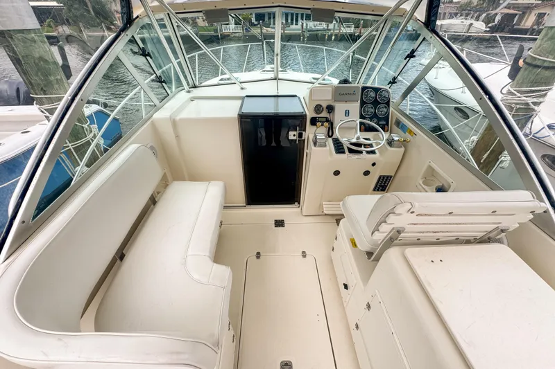 Slide: The Image of 2002 Pursuit 3000 Express boat cockpit with steering wheel and seating, docked by the water. - 22