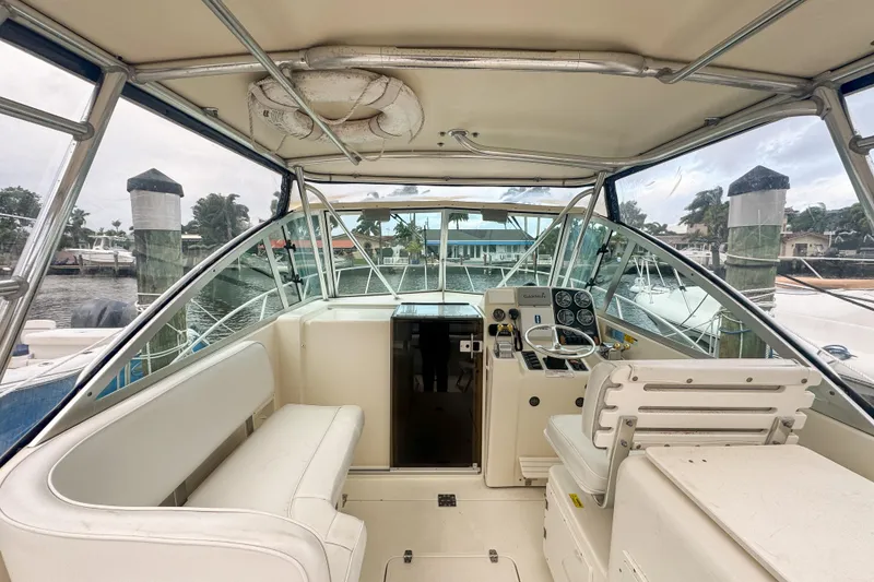 Slide: The Image of 2002 Pursuit 3000 Express boat interior with helm, seating, and marina view. - 23