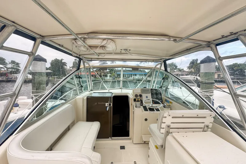 Slide: The Image of 2002 Pursuit 3000 Express boat interior with helm, seating, and marina view. - 25