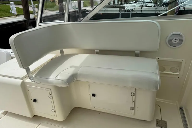 Slide: The Image of 2002 Pursuit 3000 Express boat interior with white cushioned seating and storage compartments. - 28