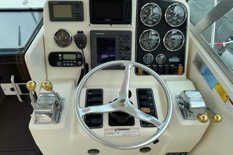 Slide: The Image of 2002 Pursuit 3000 Express boat dashboard with steering wheel and navigation instruments. - 33