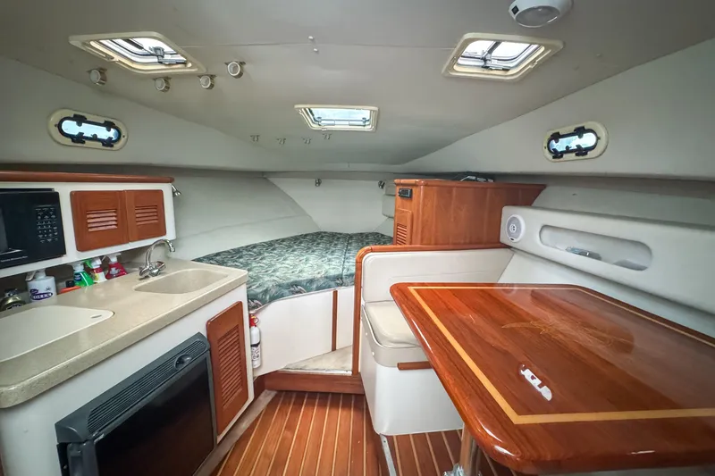 Slide: The Image of 2002 Pursuit 3000 Express cabin interior with kitchenette, bed, and wooden table. - 41