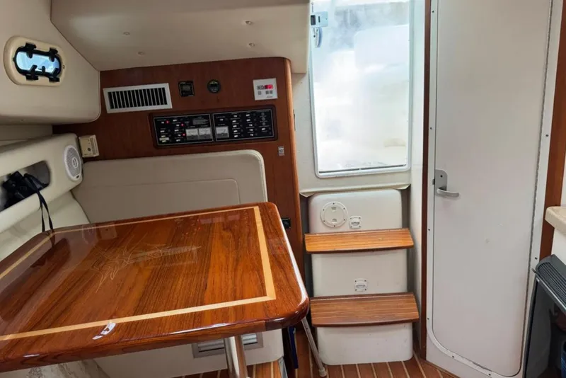 Slide: The Image of Interior of a 2002 Pursuit 3000 Express boat with wooden table and steps. - 42