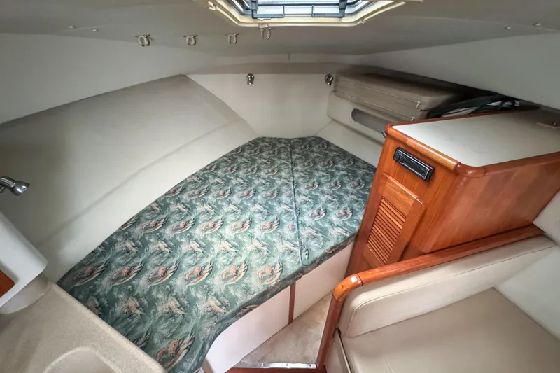 Slide: The Image of 2002 Pursuit 3000 Express cabin interior with patterned bedding and wooden cabinetry. - 44