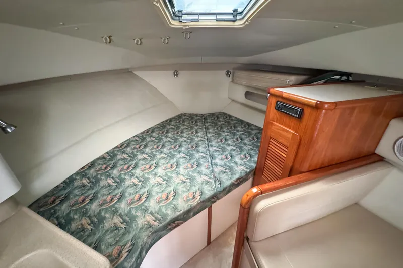 Slide: The Image of 2002 Pursuit 3000 Express cabin interior with patterned bedding and wooden cabinetry. - 45