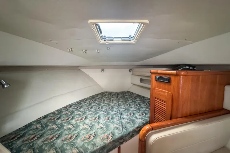 Slide: The Image of 2002 Pursuit 3000 Express cabin interior with patterned bedding and wooden cabinetry. - 46