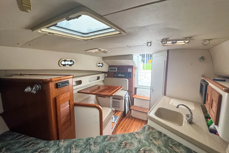 Slide: The Image of Interior of a 2002 Pursuit 3000 Express boat, featuring a compact kitchen and dining area. - 49