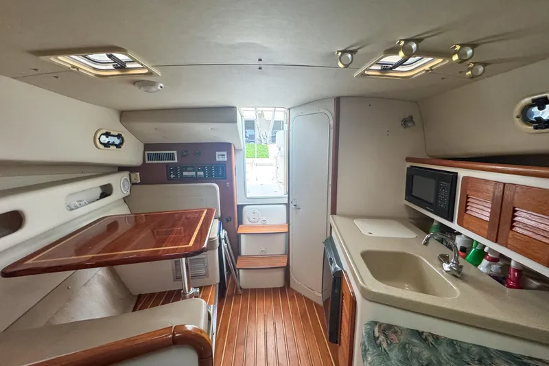 Slide: The Image of 2002 Pursuit 3000 Express boat interior with kitchenette and wooden flooring. - 53