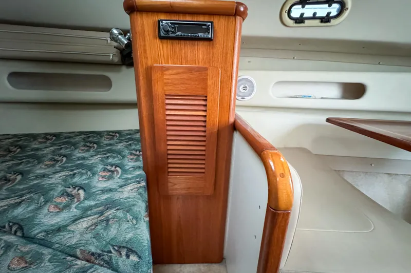 Slide: The Image of Interior of 2002 Pursuit 3000 Express boat with wood paneling and patterned bedding. - 54