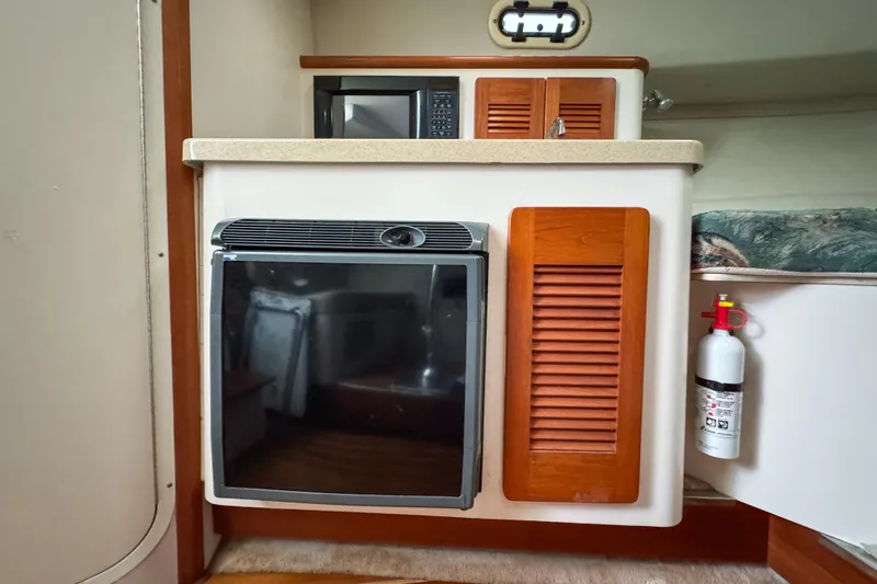 Slide: The Image of 2002 Pursuit 3000 Express cabin interior with kitchenette and fire extinguisher. - 56