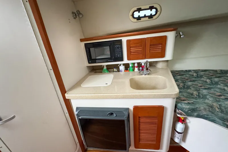 Slide: The Image of 2002 Pursuit 3000 Express cabin with kitchenette, sink, microwave, and storage cabinets. - 57