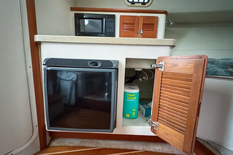 Slide: The Image of Compact galley in 2002 Pursuit 3000 Express boat with microwave, fridge, and storage. - 58