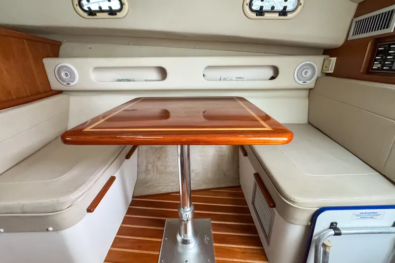 Slide: The Image of 2002 Pursuit 3000 Express cabin interior with wooden table and cushioned seating. - 59