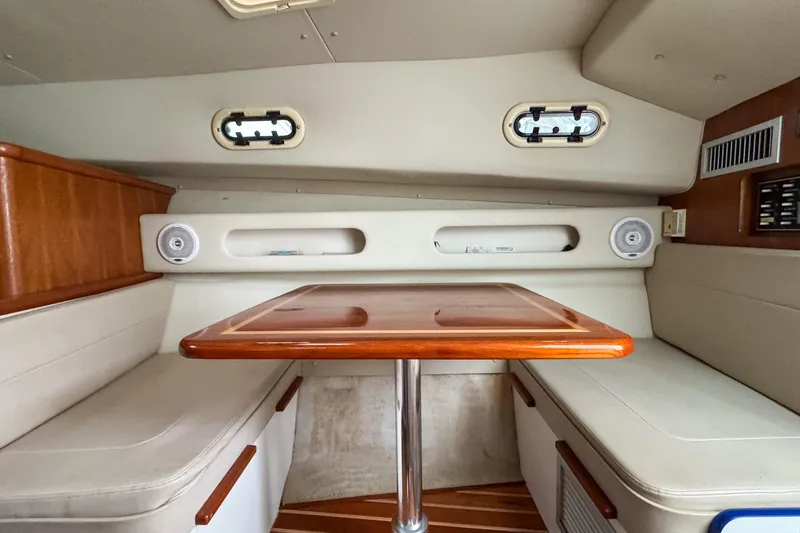 Slide: The Image of 2002 Pursuit 3000 Express cabin interior with wooden table and cushioned seating. - 60