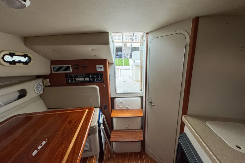Slide: The Image of Interior of a 2002 Pursuit 3000 Express boat, featuring wooden steps and cabinetry. - 65