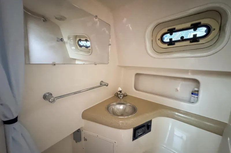 Slide: The Image of 2002 Pursuit 3000 Express boat bathroom with sink, mirror, and porthole window. - 71