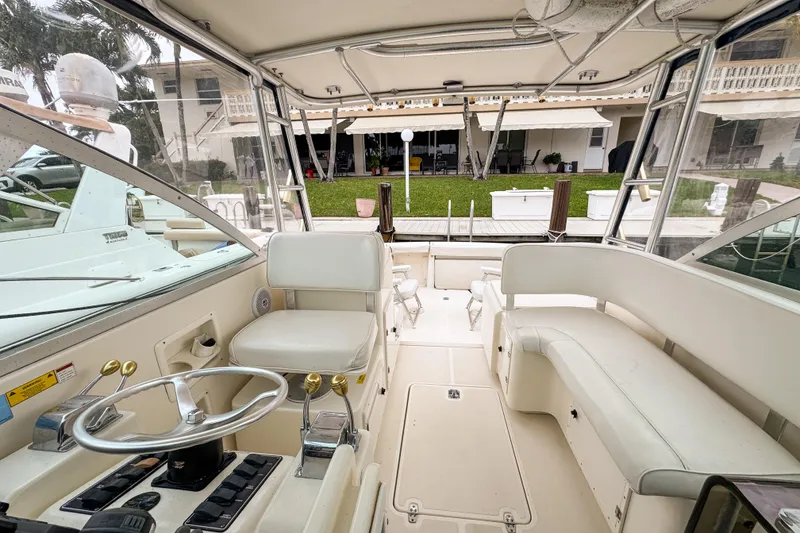 Slide: The Image of 2002 Pursuit 3000 Express boat interior with helm, seating, and dock view. - 77