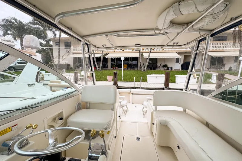 Slide: The Image of 2002 Pursuit 3000 Express boat interior with helm, seating, and dock view. - 78