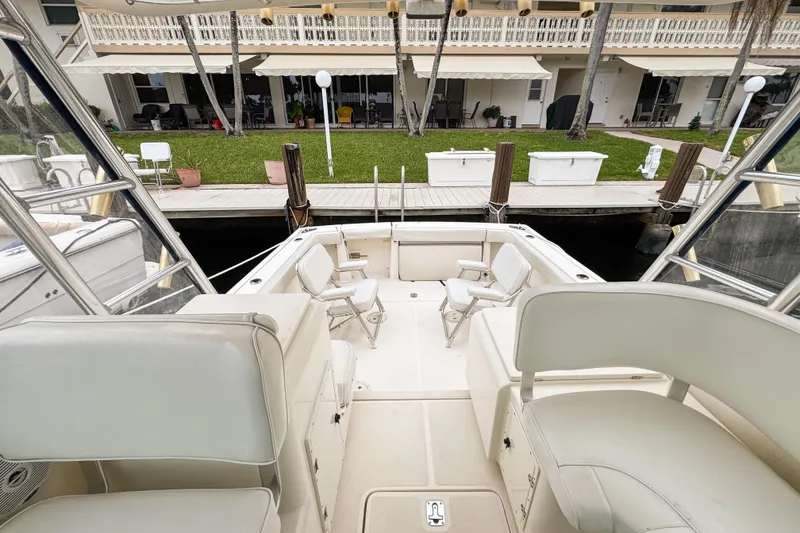 Slide: The Image of 2002 Pursuit 3000 Express boat interior with seating, docked near waterfront property. - 80
