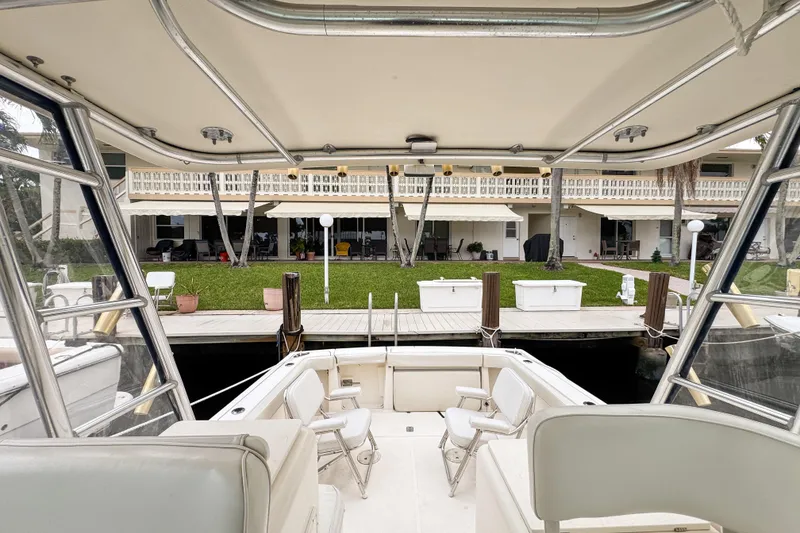 Slide: The Image of 2002 Pursuit 3000 Express boat docked near waterfront property with lush greenery. - 81