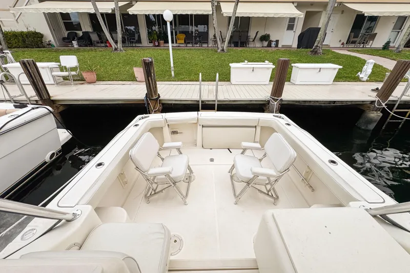 Slide: The Image of 2002 Pursuit 3000 Express boat with seating, docked near a waterfront property. - 83