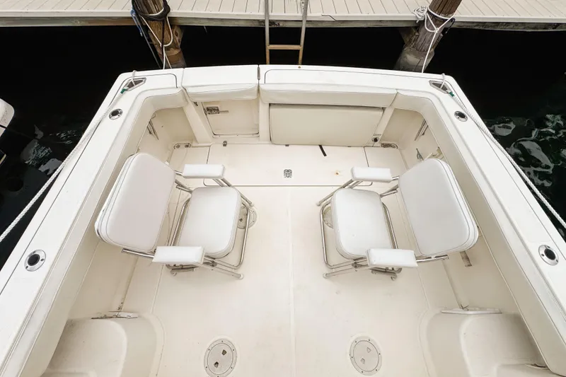 Slide: The Image of 2002 Pursuit 3000 Express boat deck with two white chairs, docked at marina. - 85