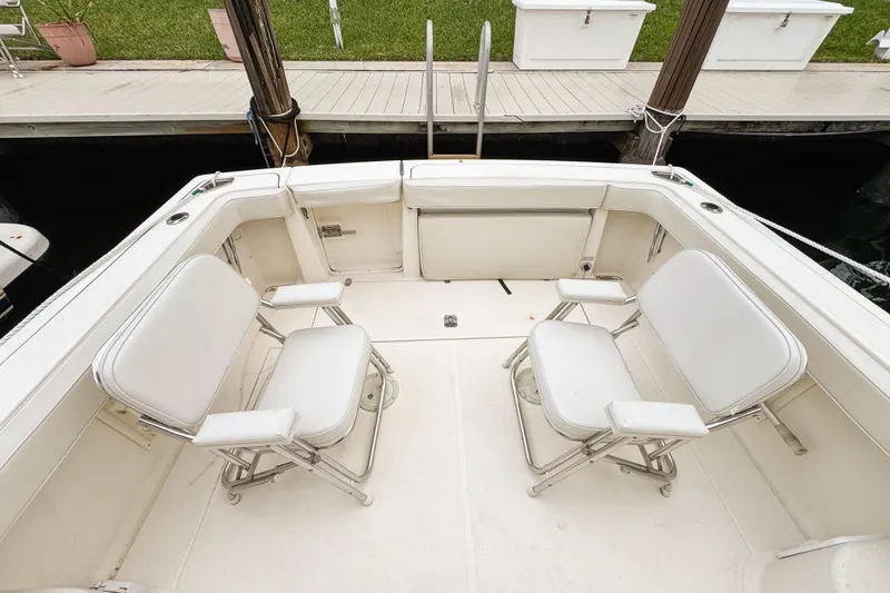 Slide: The Image of 2002 Pursuit 3000 Express boat deck with two white chairs, docked by a wooden pier. - 86