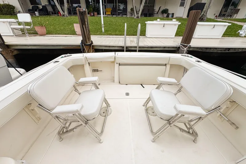 Slide: The Image of 2002 Pursuit 3000 Express boat deck with two white chairs, dockside view. - 87