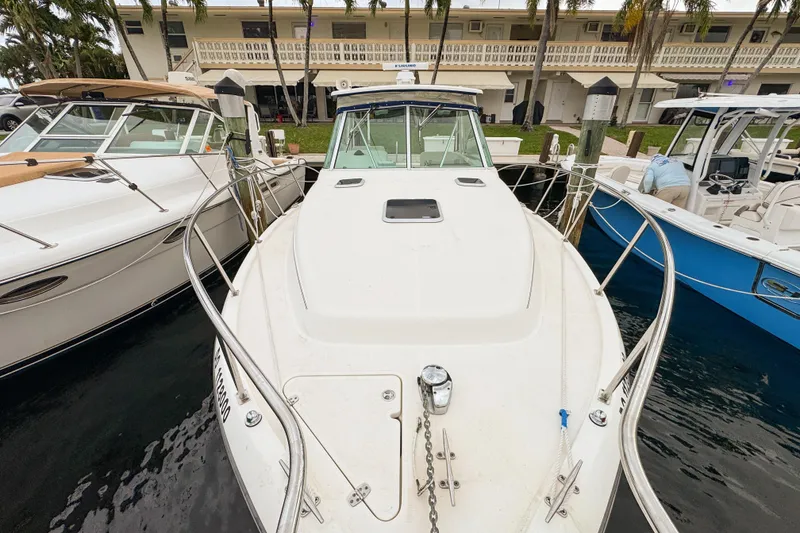 Slide: The Image of 2002 Pursuit 3000 Express boat docked between two other boats. - 90