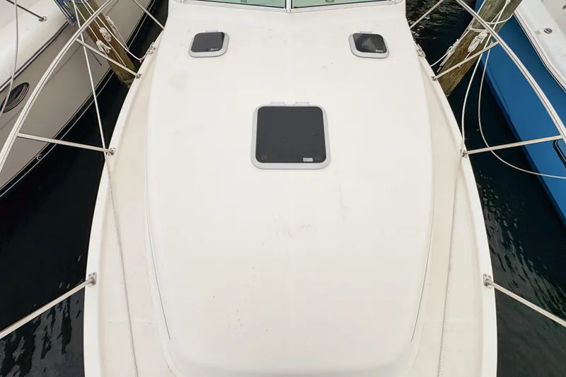 Slide: The Image of 2002 Pursuit 3000 Express boat deck with hatches, docked beside other vessels. - 93