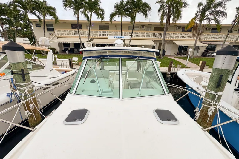 Slide: The Image of 2002 Pursuit 3000 Express boat docked, surrounded by palm trees and waterfront buildings. - 98