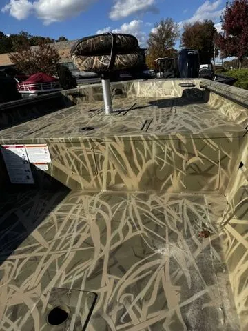 Slide: The Image of 2025 Crestliner 1860 Retriever Jon Deluxe boat with camouflage design under a blue sky. - 6