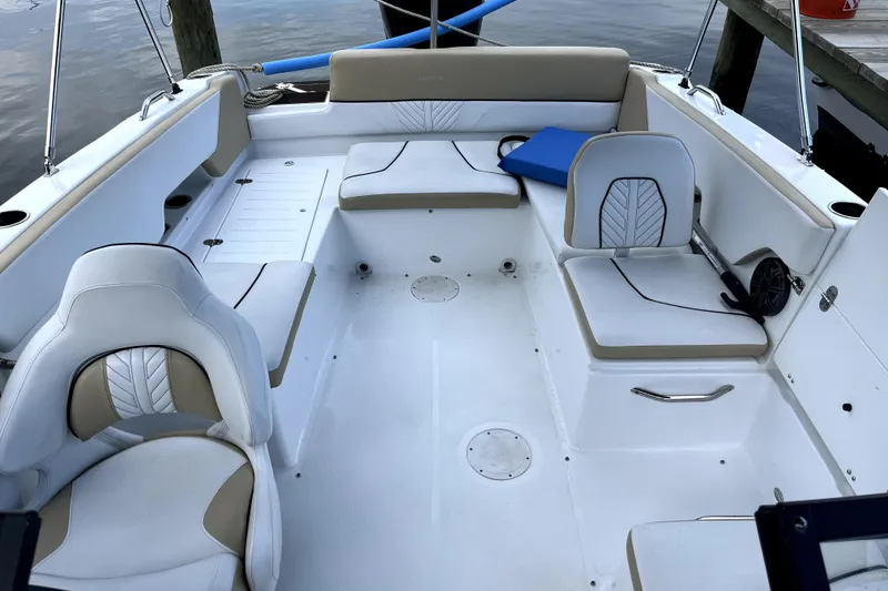 Slide: The Image of 2022 Glastron GTD 220 boat interior with white and beige seating, docked by the water. - 5
