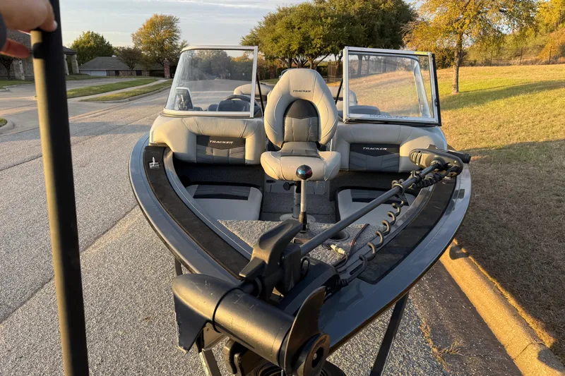 Slide: The Image of 2018 Tracker Targa 18 WT boat interior with seating and windshield, parked on a suburban street. - 34