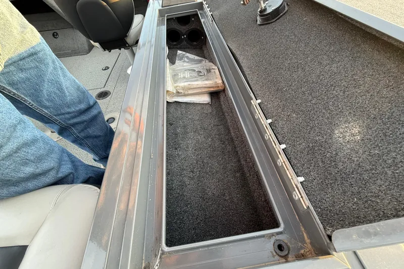 Slide: The Image of 2018 Tracker Targa 18 WT boat interior with open storage compartment, grassy landscape background. - 65