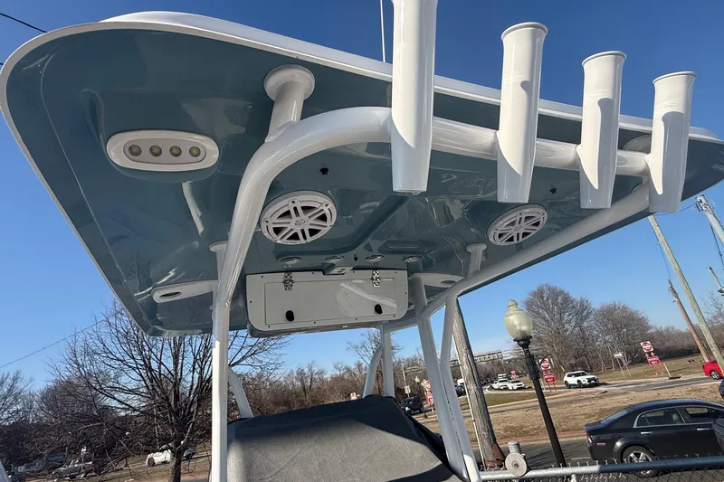 Slide: The Image of 2026 Sea Hunt Ultra 234 boat T-top with rod holders and speakers, under clear blue sky. - 12