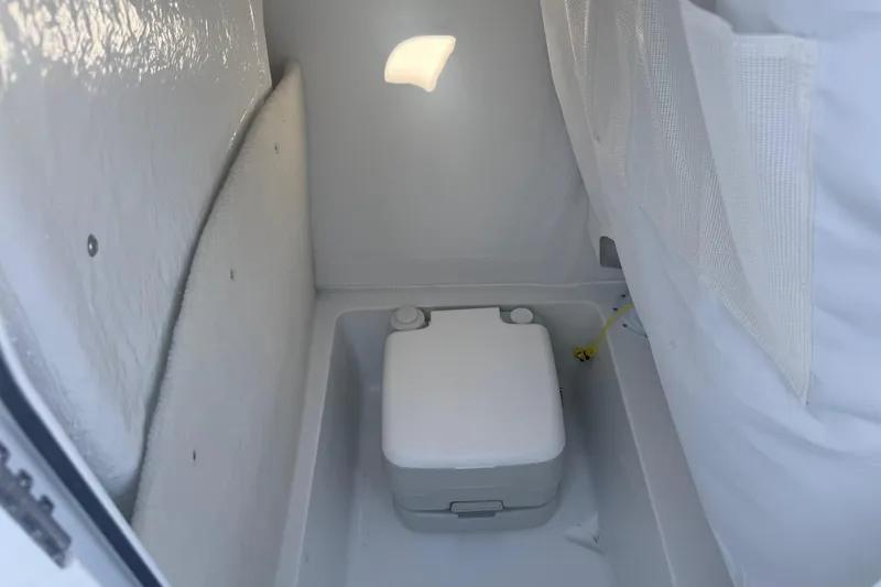 Slide: The Image of Interior of 2026 Sea Hunt Ultra 234 boat featuring a compact portable toilet. - 24